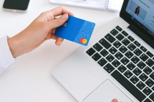 Person making an online purchase with a credit card on a laptop, showcasing modern ecommerce technology.