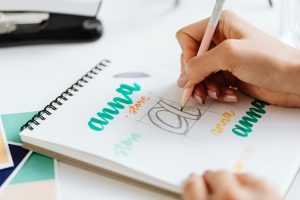 Close-up of a woman hand lettering colorful text in a notebook.